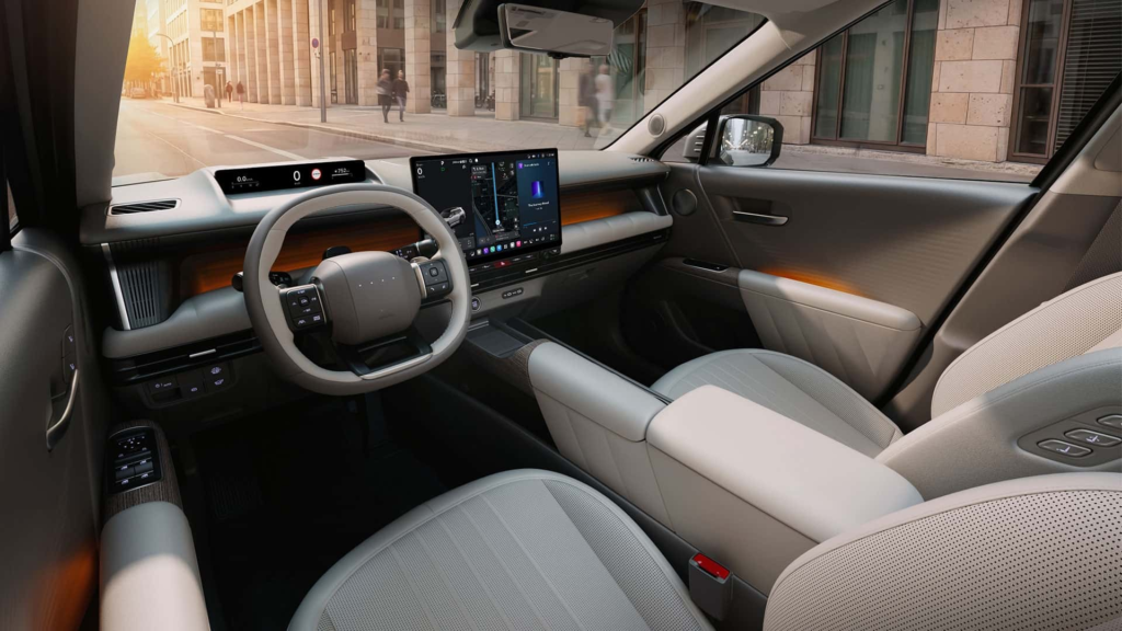 2027 Hyundai Tucson interior showing the Pleos touchscreen, wood trim, and squared two-spoke steering wheel