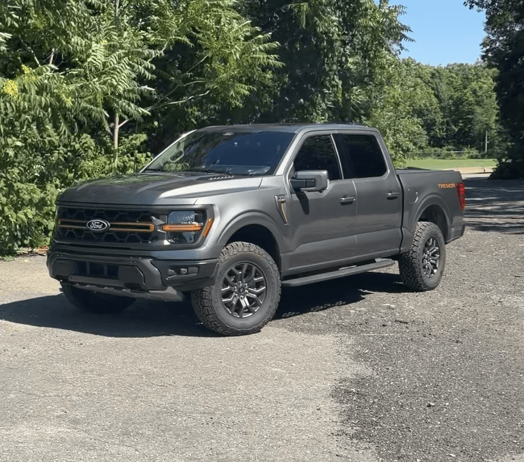 2025 Ford F-150 Tremor front three-quarter view in Carbonized Gray with the amber grille bar and Tremor bedside graphics