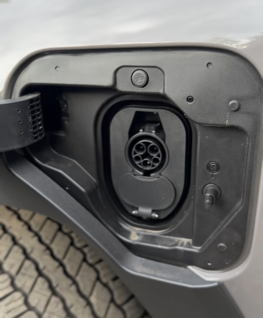 Charge port of the 2026 Toyota RAV4 Woodland plug-in hybrid with the all-terrain tire tread visible below