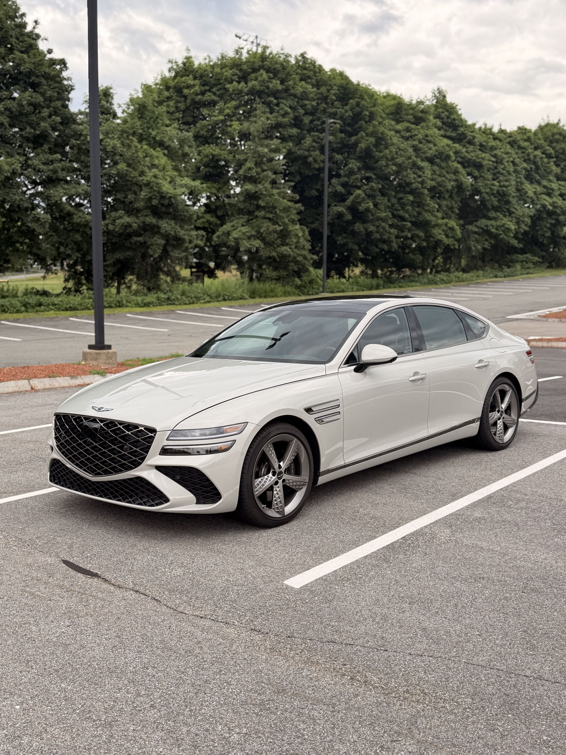 White 2025 Genesis G80 3.5T Sport Prestige front three quarter in a parking lot