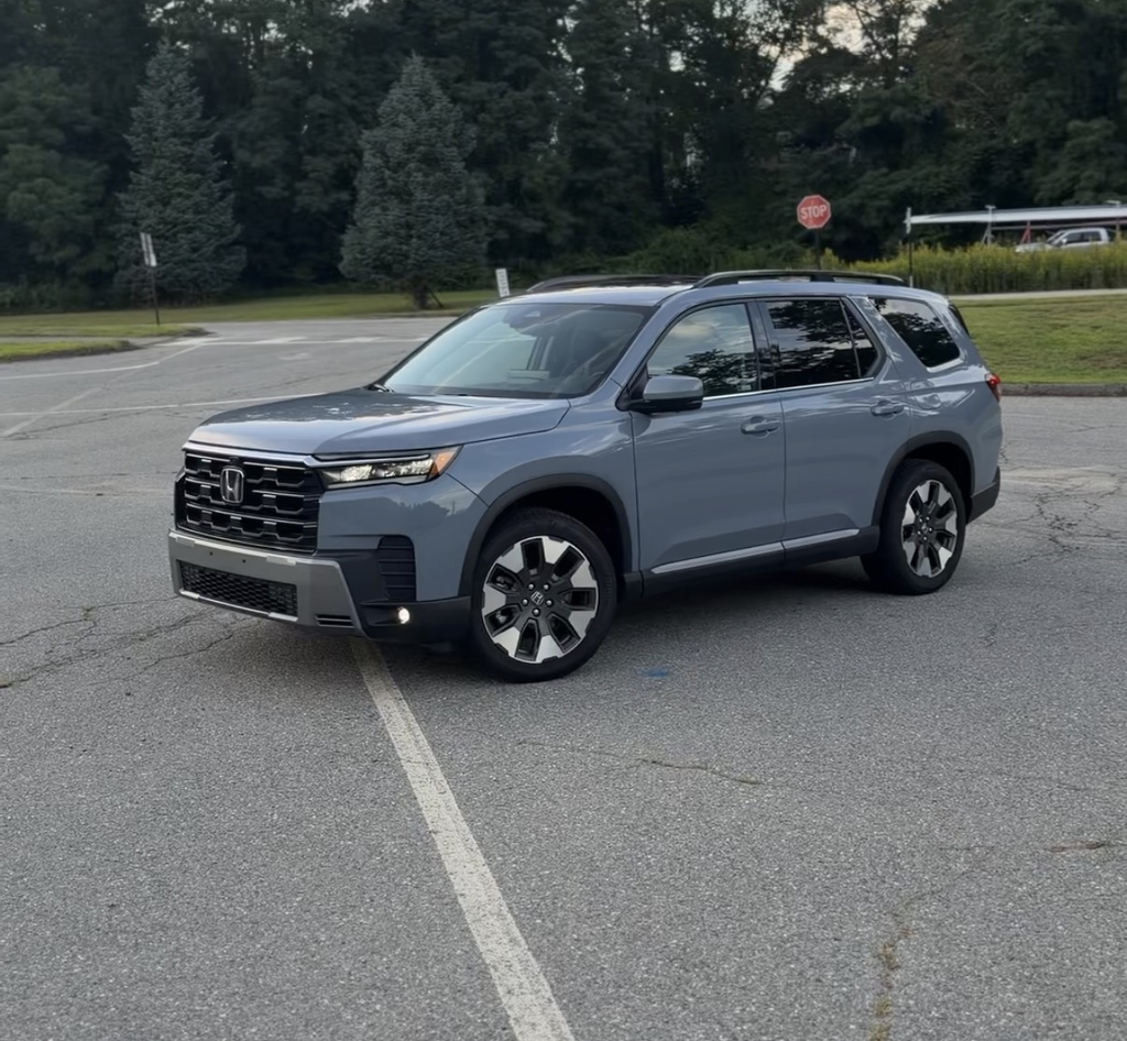 2026 Honda Pilot Elite front three-quarter view in Diffused Sky Blue parked on an empty lot