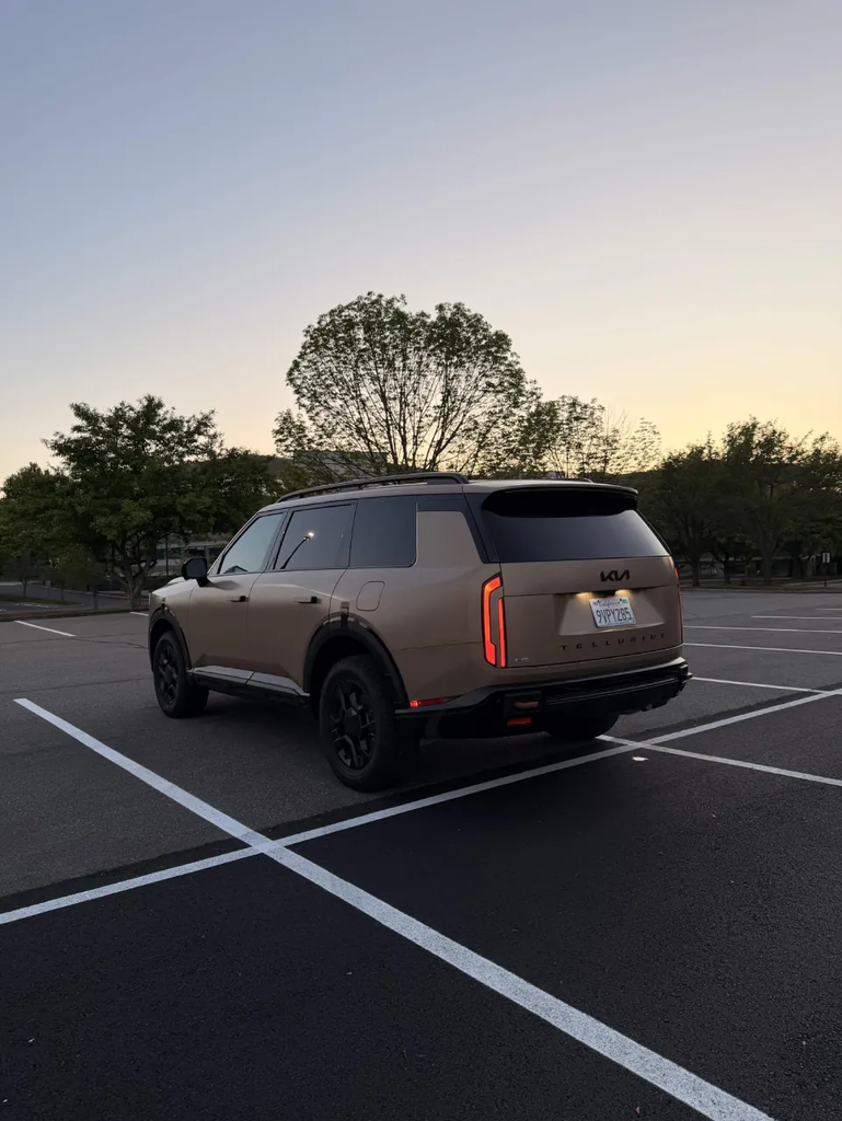 2027 Kia Telluride X-Pro rear three-quarter view in matte Terrain at dusk with the vertical taillights lit