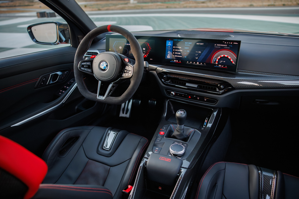 BMW M3 CS Handschalter interior showing the six-speed manual shifter, Alcantara steering wheel, and curved display