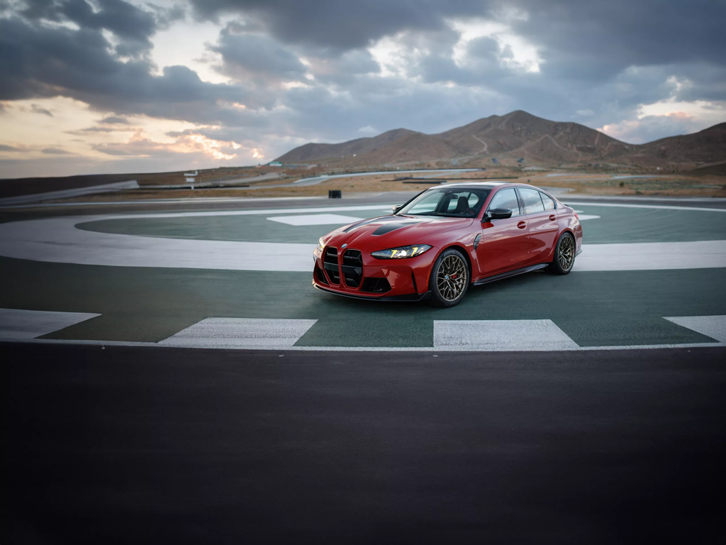 BMW M3 CS Handschalter in red parked on a skidpad with mountains behind
