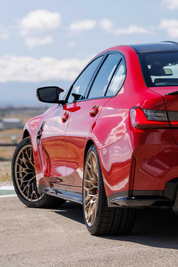 BMW M3 CS Handschalter rear three-quarter detail in red with bronze wheels and carbon rear diffuser