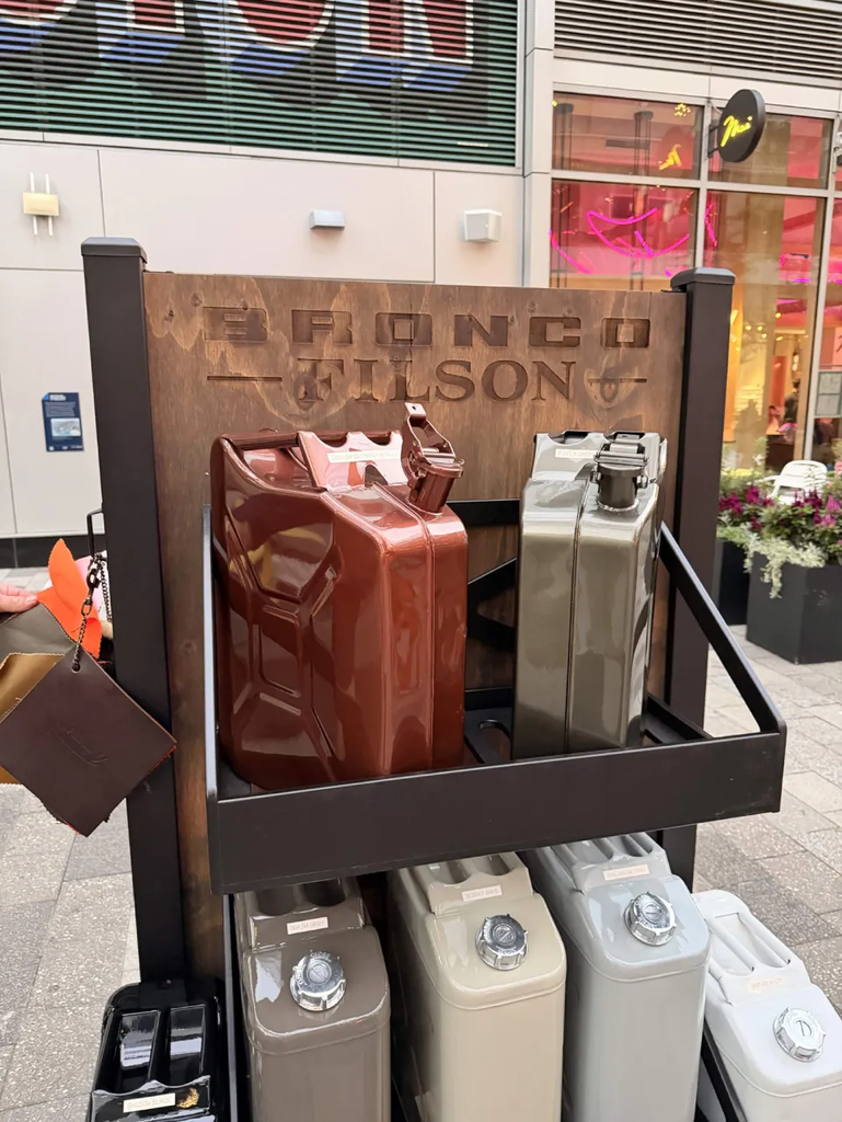 Bronco Filson display with painted jerry cans in the launch colors under a carved wood Bronco Filson sign