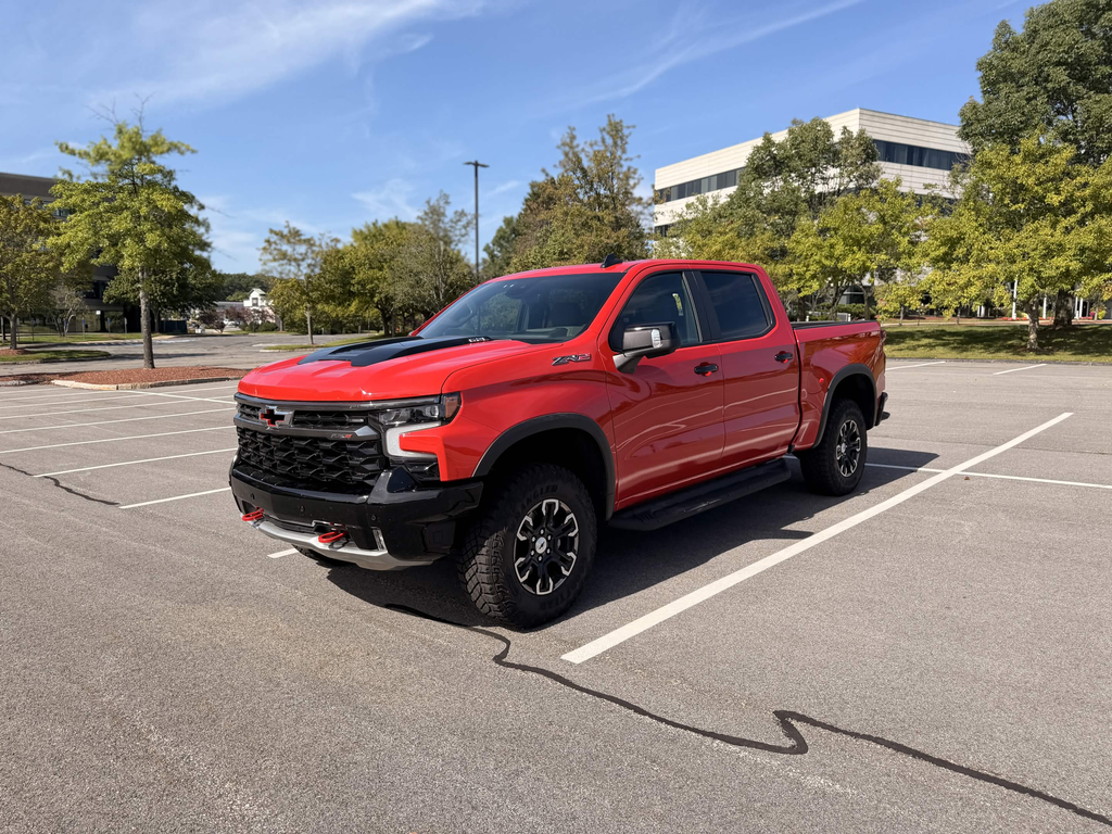2026 Chevrolet Silverado ZR2 front three-quarter view in Red Hot with the black hood insert and Goodyear mud-terrain tires