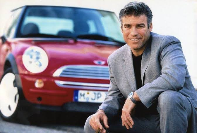 A young Frank Stephenson kneeling beside the red R50 modern Mini Cooper he designed
