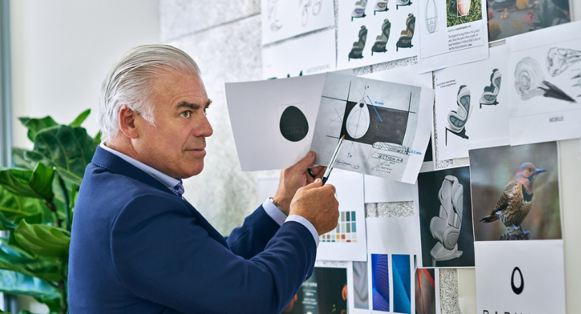 Frank Stephenson at his design studio wall pointing at sketches and reference photos