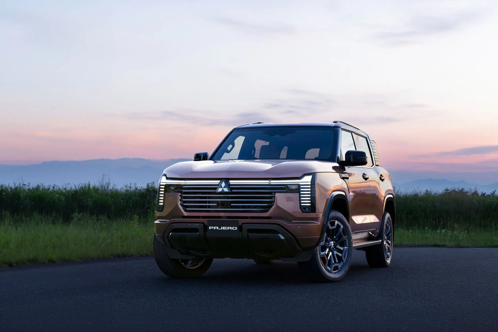 2027 Mitsubishi Pajero front view in bronze at dusk with the illuminated grille and Pajero-badged bumper