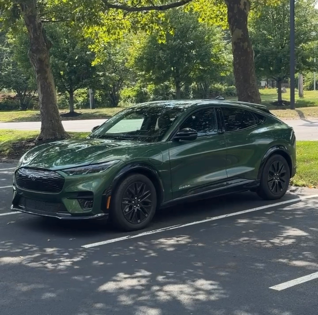 2026 Ford Mustang Mach-E Premium front three-quarter view in Eruption Green parked under trees