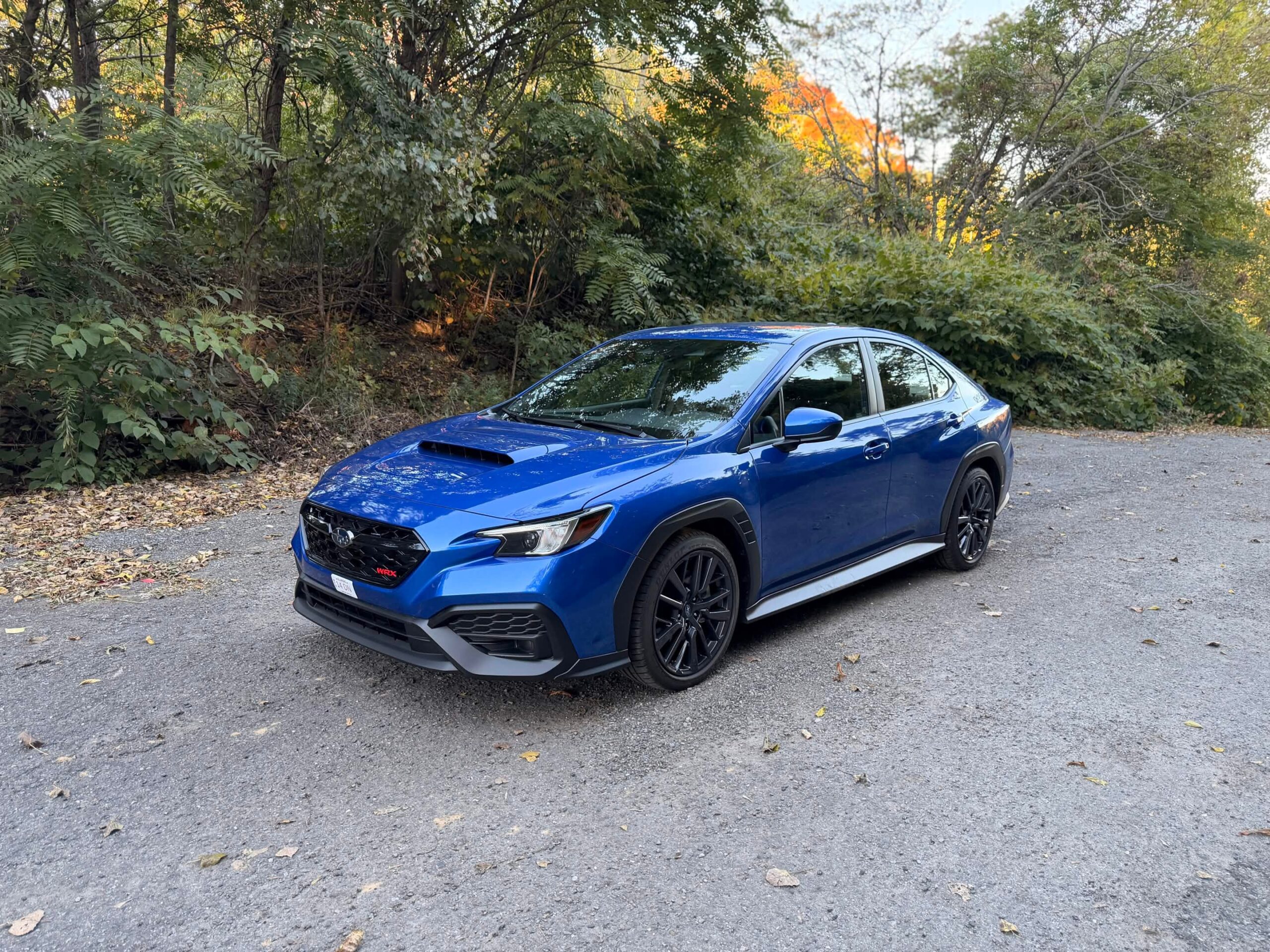 2026 Subaru WRX base in WR Blue Pearl, front three quarter view parked on a gravel road in fall foliage
