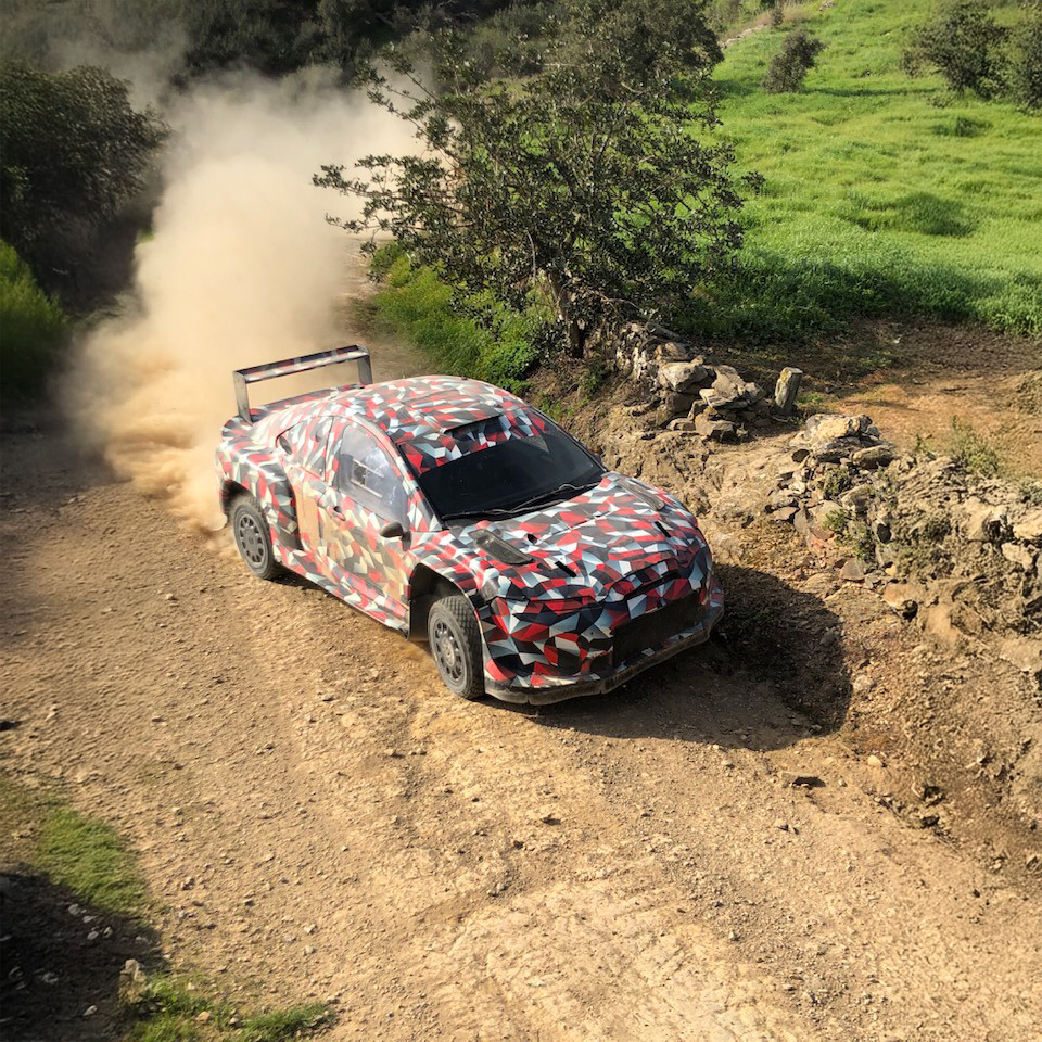 Camouflaged Toyota WRC 2027 rally prototype testing on a gravel stage in Portugal