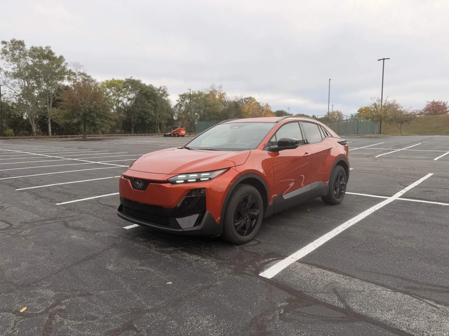 2026 Subaru Uncharted Sport in orange, front three quarter view in a parking lot with fall foliage