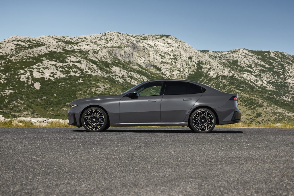 Grey BMW 320 side profile parked below rocky mountains
