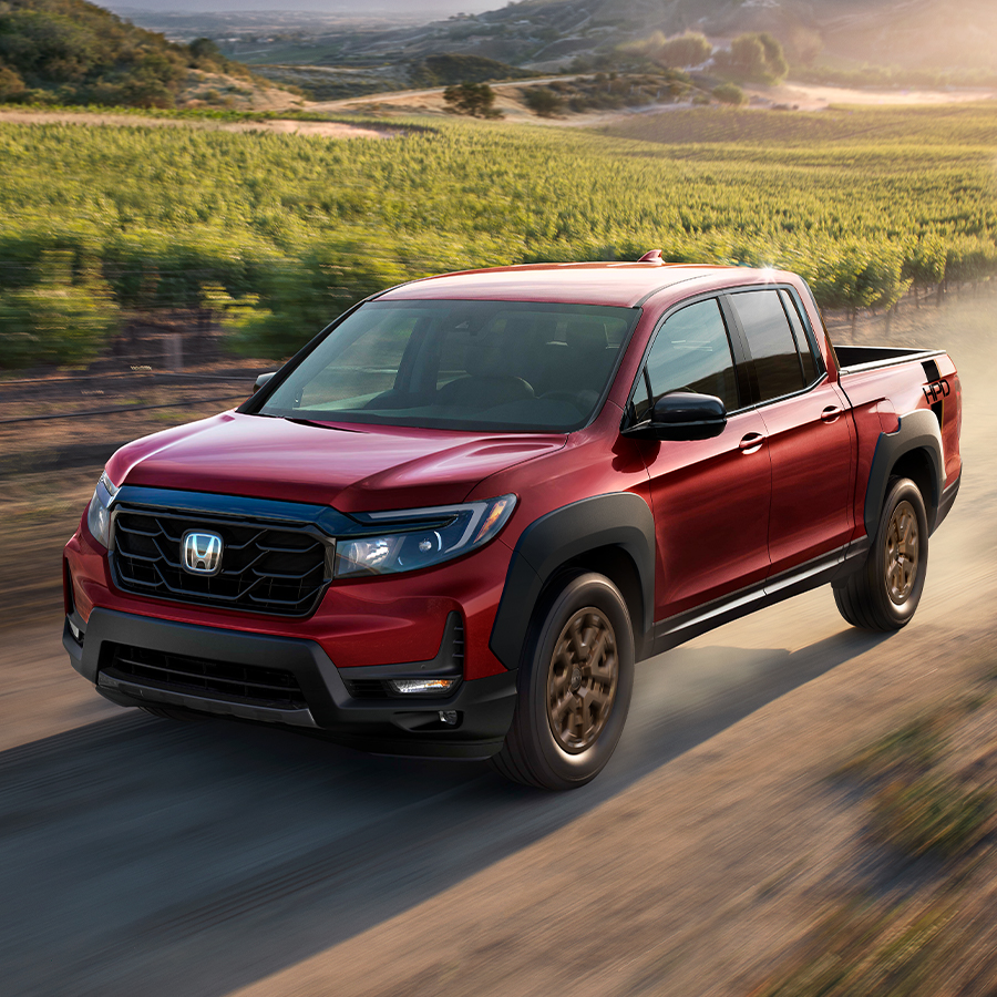 Red Honda Ridgeline driving on a dirt road