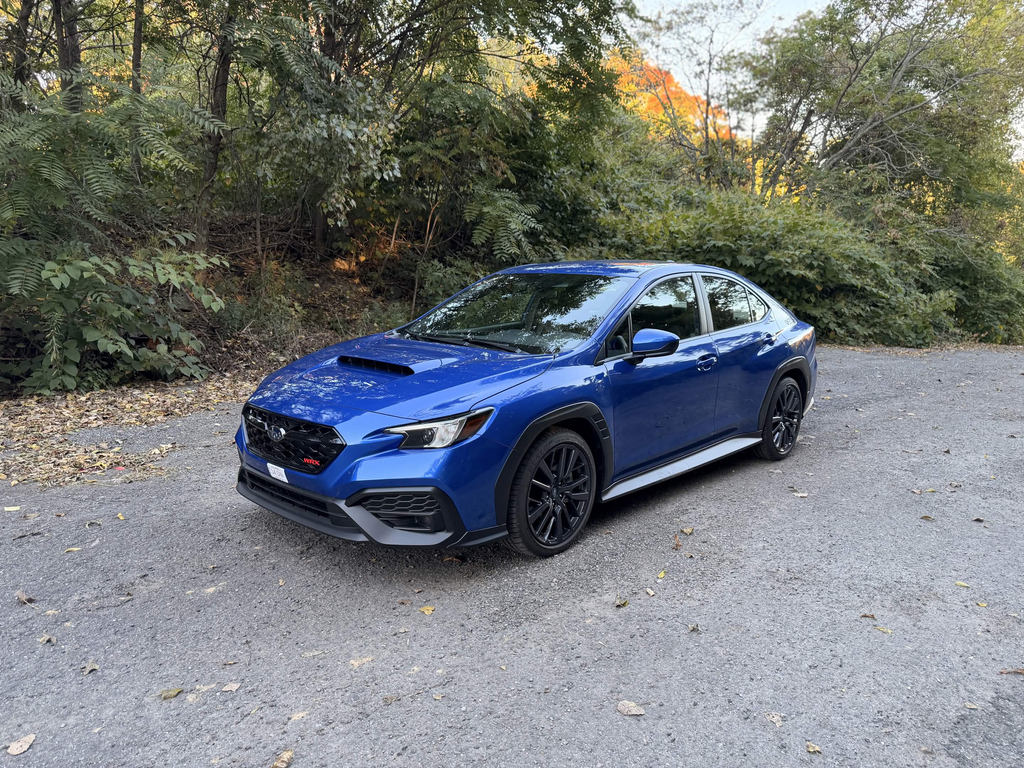 2026 Subaru WRX base in WR Blue Pearl, front three quarter view parked on a gravel road in fall foliage